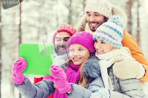 Image of smiling friends with tablet pc in winter forest