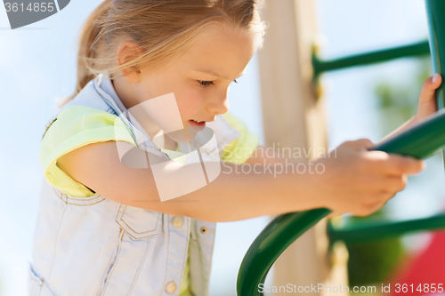 Image of happy little girl climbing on children playground