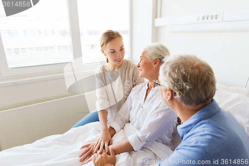 Image of happy family visiting senior woman at hospital