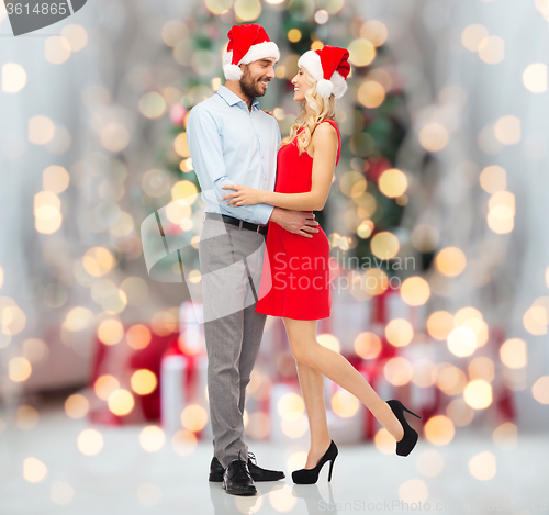 Image of happy couple in santa hats hugging