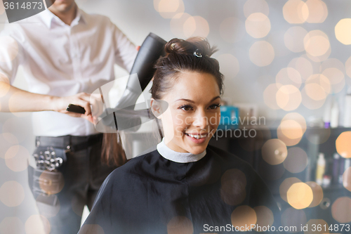 Image of happy woman with stylist making hairdo at salon