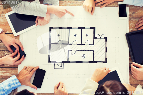 Image of business team with blueprint and gadgets