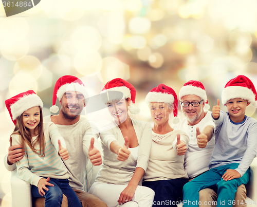 Image of happy family in santa hats showing thumbs up