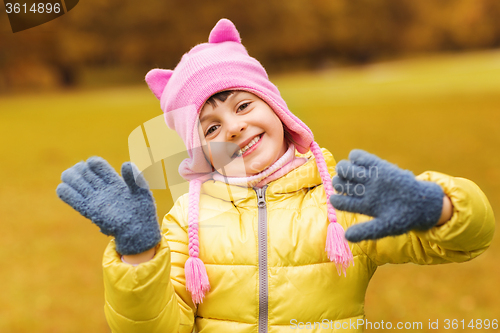 Image of happy beautiful little girl waving hands outdoors