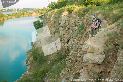 Image of Young caucasian man with backpack sitting on the top of hill