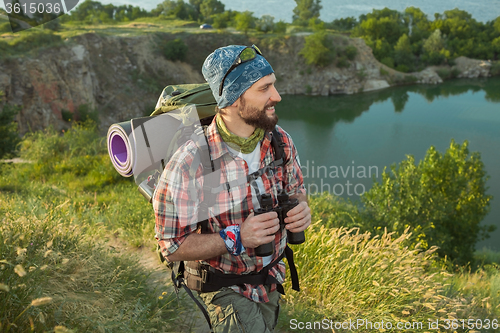 Image of Young caucasian man with backpack walking on the top of hill