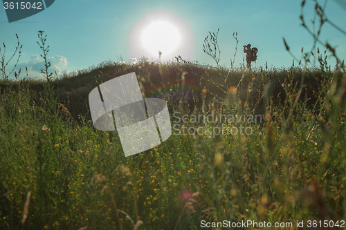 Image of Young caucasian man with backpack walking on a green meadow