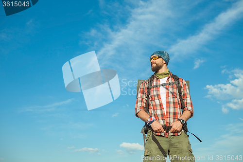 Image of Young caucasian man with backpack standing on the top of hill