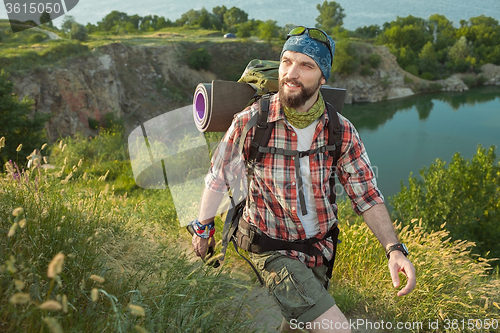 Image of Young caucasian man with backpack walking on the top of hill