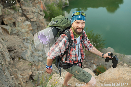 Image of Young caucasian man with backpack climbing the rock