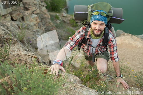 Image of Young caucasian man with backpack climbing the rock