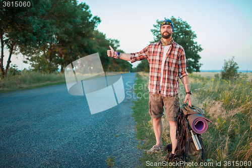 Image of Young  caucasian tourist hitchhiking along a road.