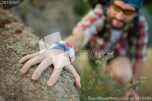 Image of Young caucasian man with backpack climbing the rock