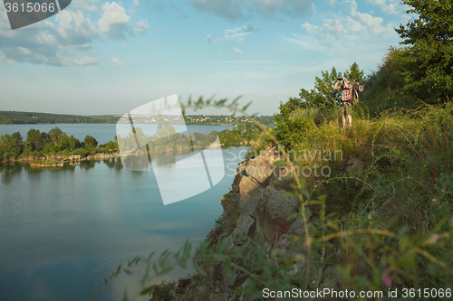 Image of Young caucasian man with backpack standing on the top of hill