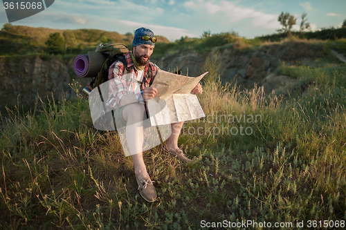 Image of Young caucasian man with backpack sitting on the top of hill