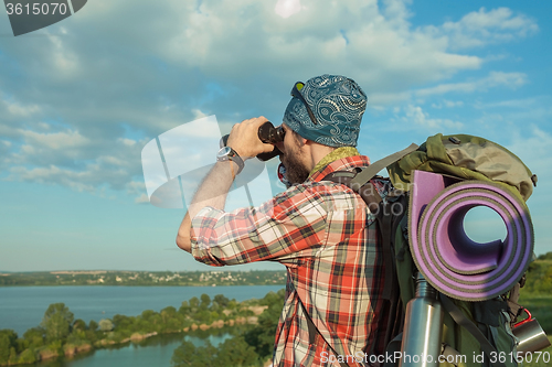 Image of Young caucasian man with backpack standing on the top of hill