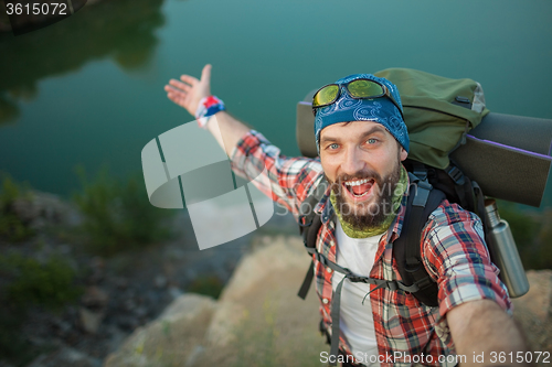 Image of Young caucasian man with backpack standing on the top of hill