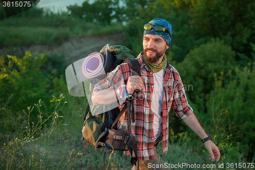 Image of Young caucasian man with backpack walking on the top of hill