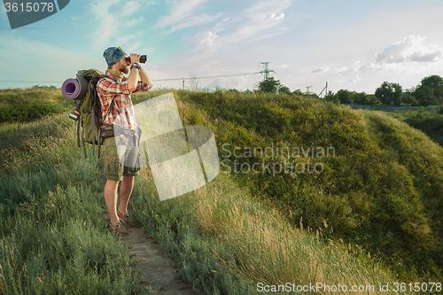 Image of Young caucasian man with backpack standing on the top of hill