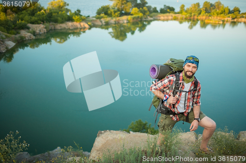 Image of Young caucasian man with backpack climbing the rock