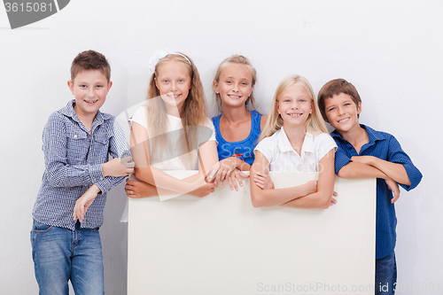 Image of Happy smiling group of kids, boys and girls, showing board 