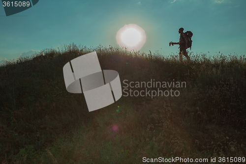 Image of Young caucasian man with backpack walking on a green meadow