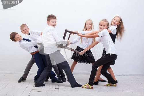 Image of Kids playing tug of chair - girls versus boys,