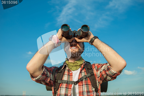 Image of Young caucasian man with backpack standing on the top of hill