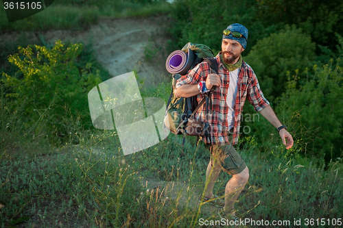 Image of Young caucasian man with backpack walking on the top of hill