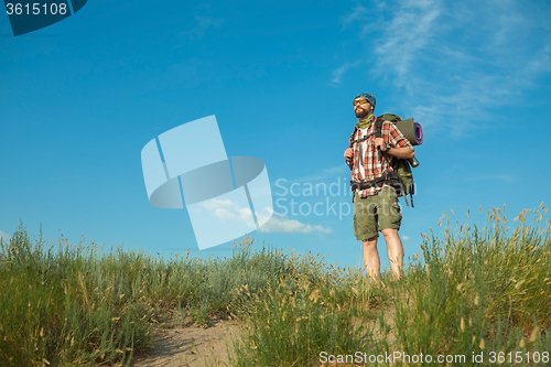 Image of Young caucasian man with backpack standing on the top of hill