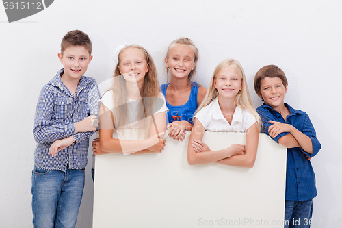 Image of Happy smiling group of kids, boys and girls, showing board 