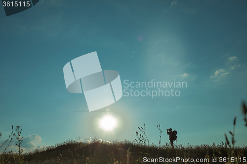 Image of Young caucasian man with backpack walking on a green meadow