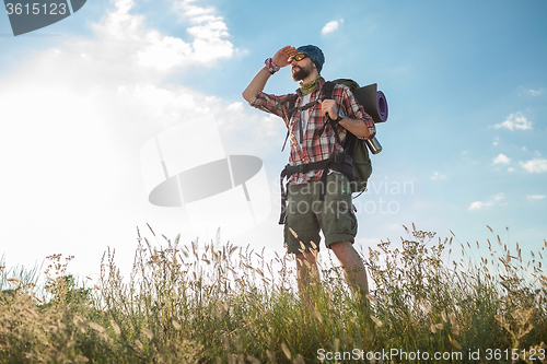 Image of Young caucasian man with backpack standing on the top of hill