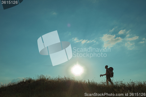 Image of Young caucasian man with backpack walking on a green meadow