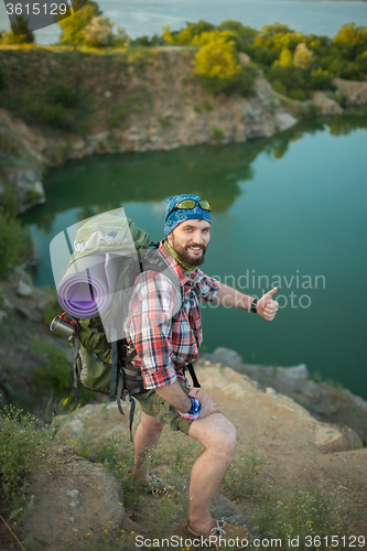 Image of Young caucasian man with backpack standing on the top of hill