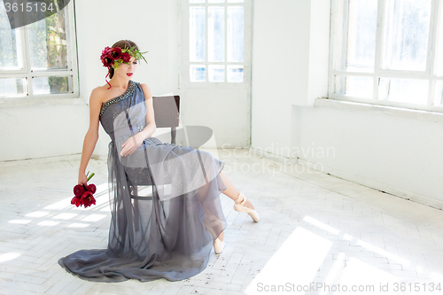 Image of The beautiful ballerina sirtting in long gray dress 