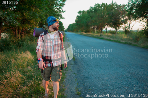 Image of Young caucasian tourist hitchhiking along a road.