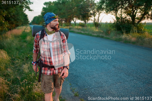 Image of Young caucasian tourist hitchhiking along a road.