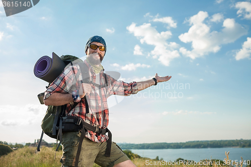 Image of Young caucasian man with backpack standing on the top of hill