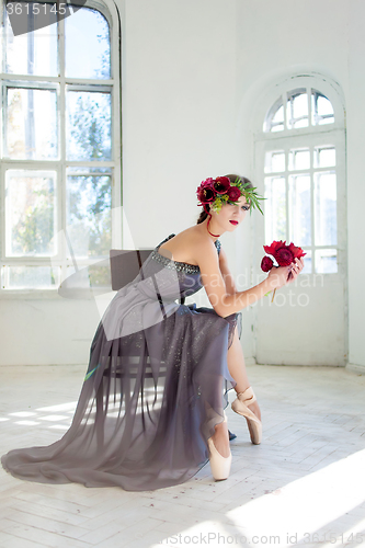 Image of The beautiful ballerina sirtting in long gray dress 