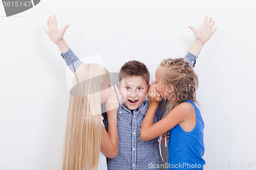 Image of Teenage girsl whispering in the ears of a secret teen boy on white  background