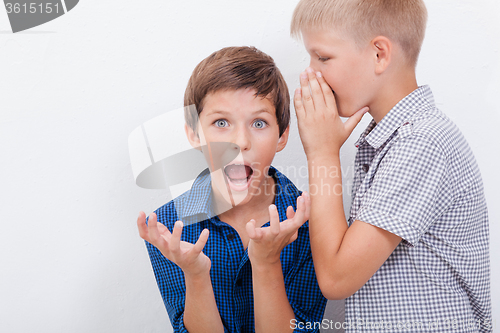 Image of Teenage boy whispering in the ear a secret to friendl on white  background