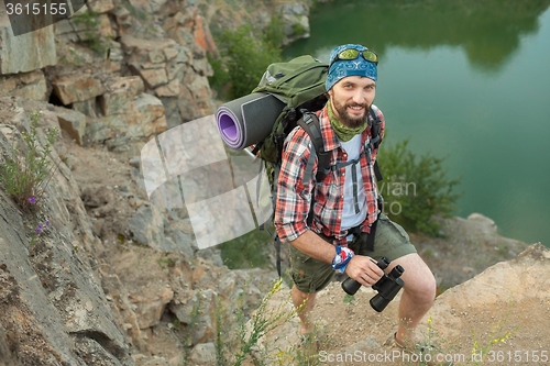 Image of Young caucasian man with backpack climbing the rock