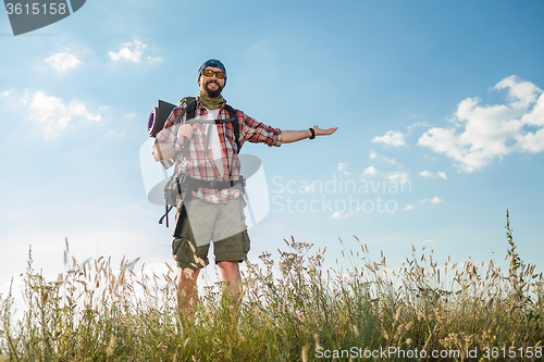 Image of Young caucasian man with backpack standing on the top of hill
