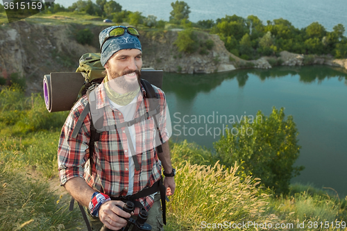 Image of Young caucasian man with backpack walking on the top of hill