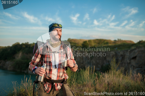 Image of Young caucasian man with backpack resting and drinking water