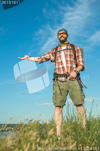 Image of Young caucasian man with backpack standing on the top of hill