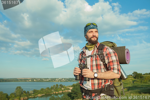 Image of Young caucasian man with backpack standing on the top of hill