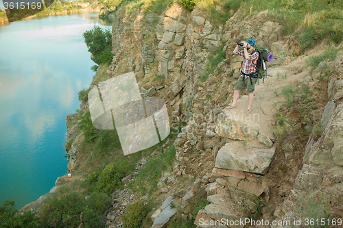 Image of Young caucasian man with backpack sitting on the top of hill