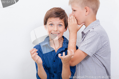 Image of Teenage boy whispering in the ear a secret to friendl on white  background